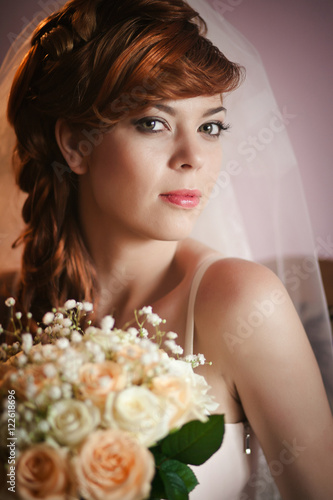 Portrait of stunning bride with red hair and shining pink lips
