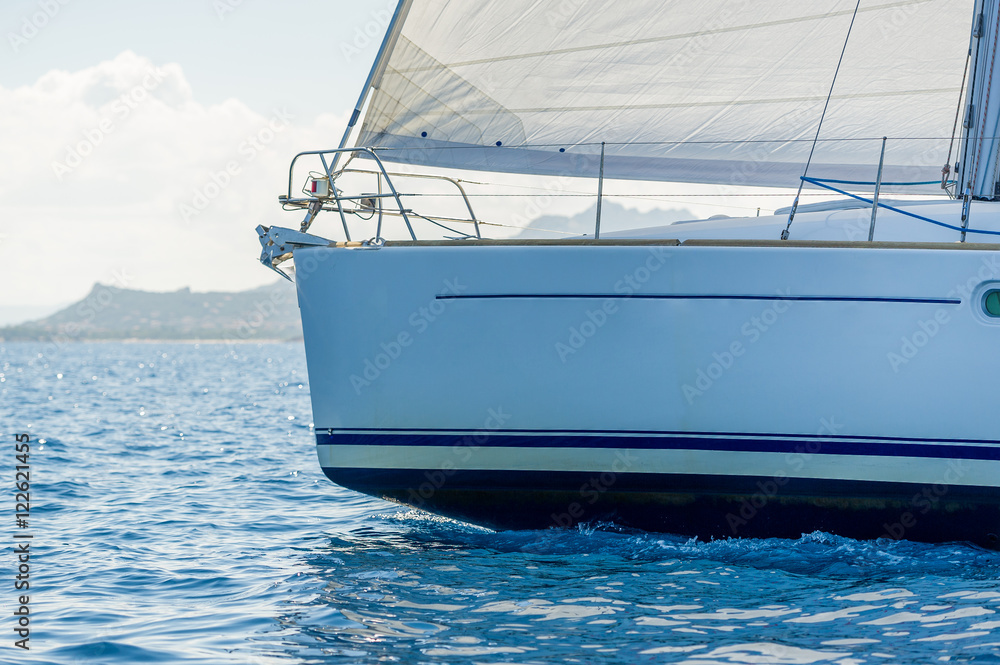 Fototapeta premium Close view against the sun at sailboat bow with hoisted headsail.