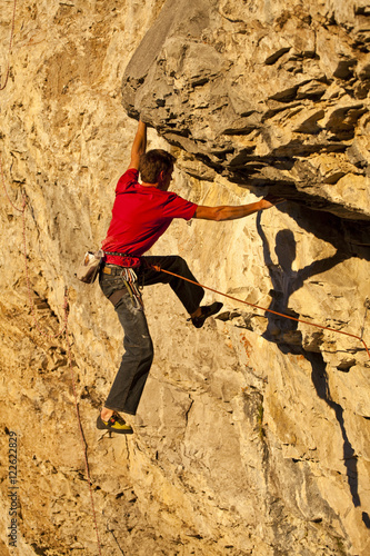 A man climbs the sport route Fire in the Sky 12b at sunset, Echo Canyon, Canmore, Alberta, Canada photo