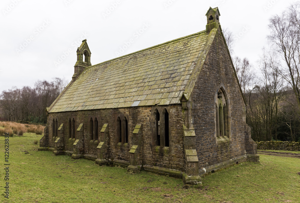 An creepy old abandoned christian church, on a gloomy overcast day, covered in moss, deep in the english countryside.