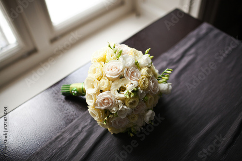 White wedding bouquet lies on dark grey cloth before the window