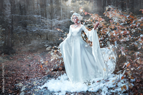 Fototapeta Fairytale Snow Queen portrait bringing winter in autumn forest.