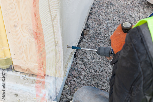 Worker use drill to make a hole in structural Insulated Panel