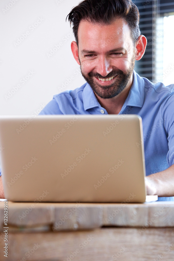 Smiling business man sitting at his desk and using laptop Smiling business man sitting at his desk and using laptop