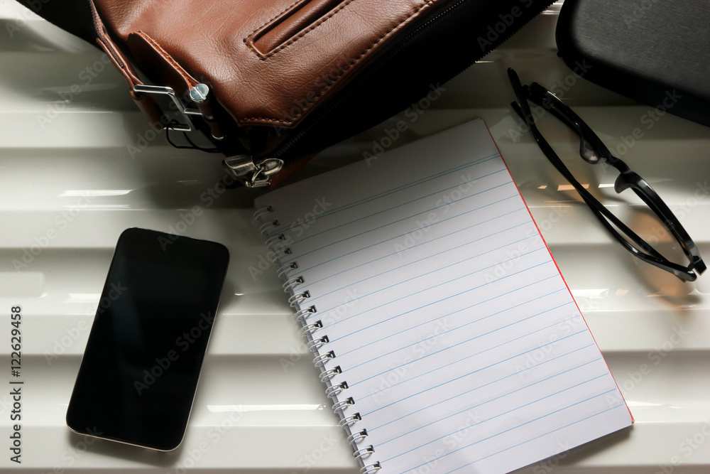 Notebook, leather bag, glasses and smart phone on desk Notebook, leather bag, glasses and smart phone on desk