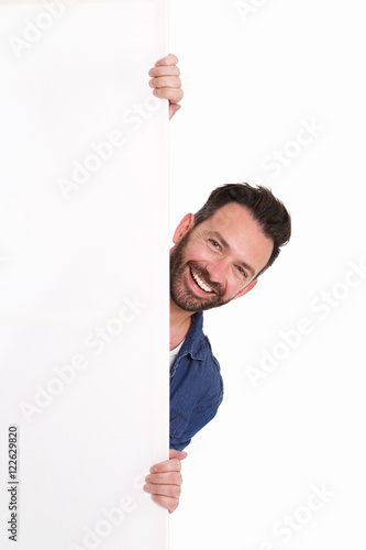 Tableau sur toile Smiling mature man peeking over blank poster sign