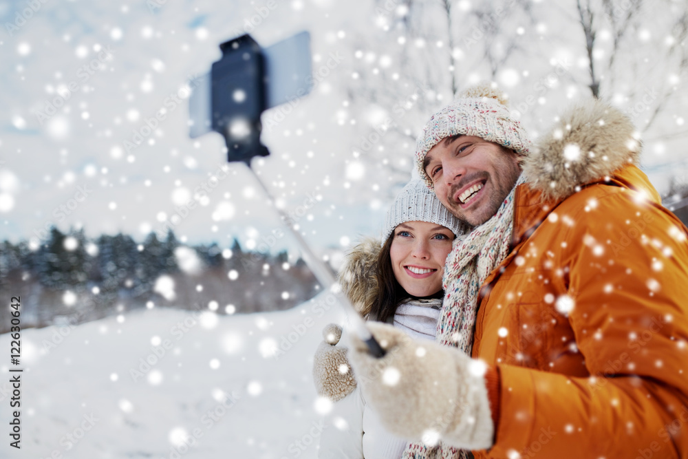 happy couple taking selfie by smartphone in winter happy couple taking selfie by smartphone in winter