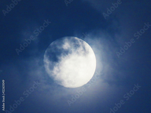 Blue sky with Full Moon and clouds rolling over it 