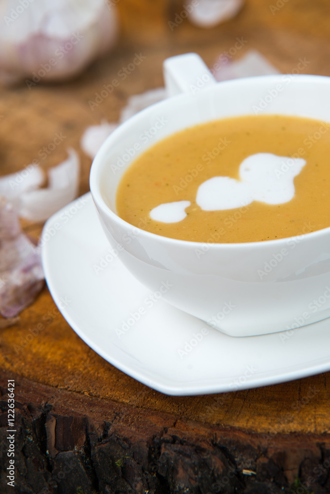 Garlic cream soup in orange bowl on wooden background. rustic country style. Garlic cream soup in orange bowl on wooden background. rustic country style.