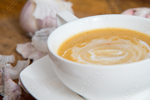 Garlic cream soup in orange bowl on wooden background. rustic country style.
