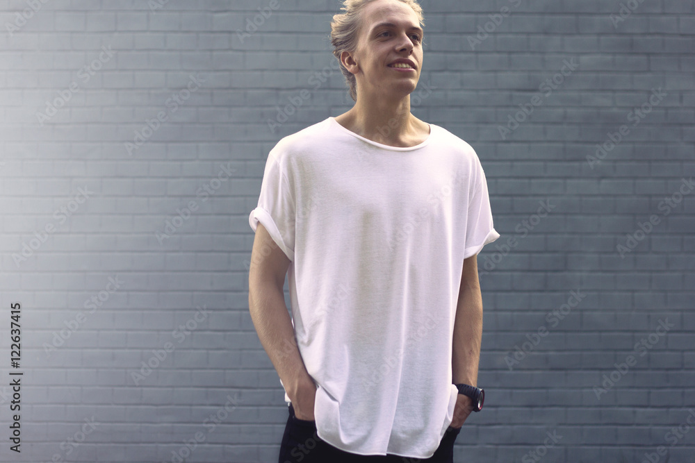 Hipster in a blank white t-shirt on the background wall Hipster in a blank white t-shirt on the background wall
