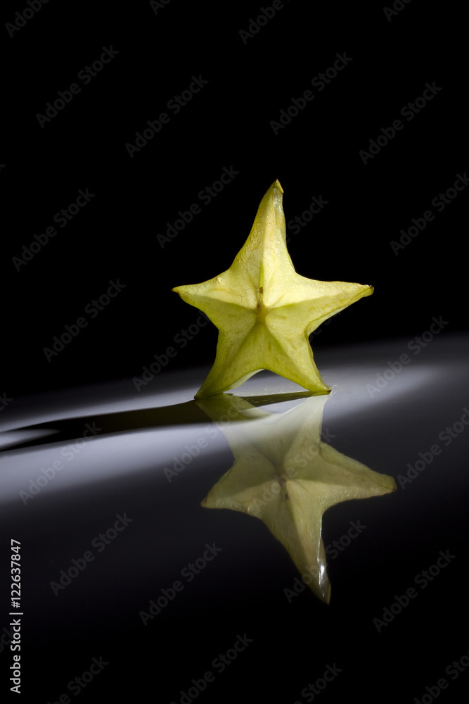 Slice of star fruit on a black background with a beautiful back light. Slice of star fruit on a black background with a beautiful back light.
