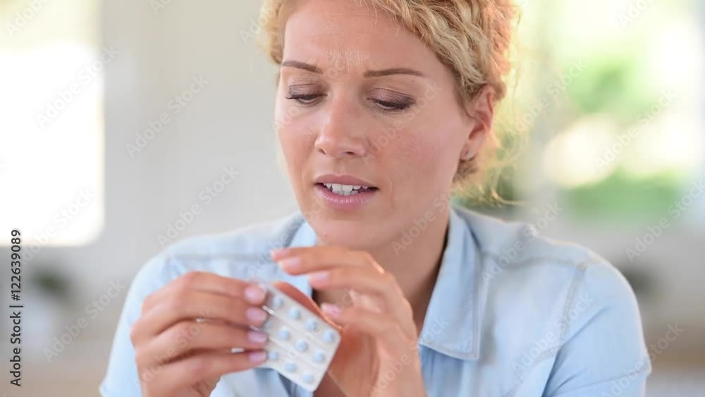 Woman at work taking pill to ease headache Woman at work taking pill to ease headache