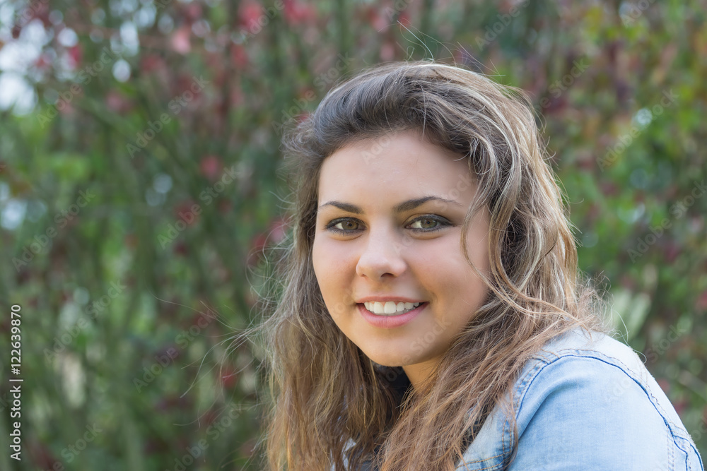Naklejka premium Portrait of smiling long hair teenage girl in outdoors. Girl is looking at the camera. 