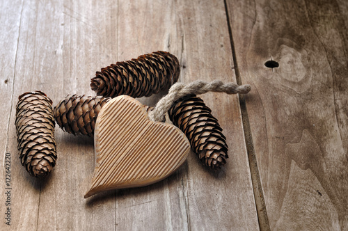 cœur avec pomme de pins sur table en bois