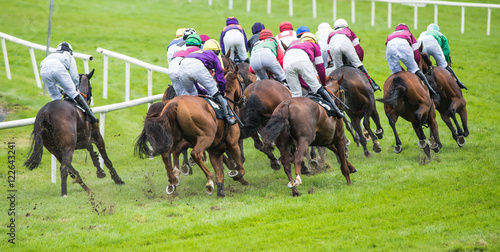 race horses and jockeys turning the track corner during a race