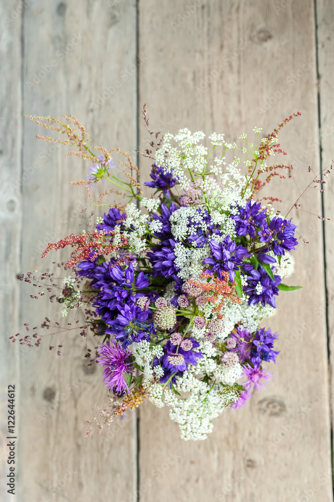 Beautiful tender bouquet of summer meadow flowers on wooden background. Floral composition in rural vintage style