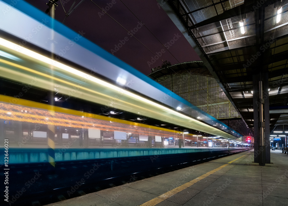 Train speeding through Prague railway station during busy night time with extended motion. Beautiful historical railway station in capital city of Czech republic.