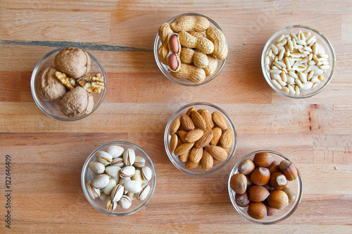 Assorted nuts in bowls: walnut, pistachios, almond, peanut, hazelnut, pine nuts