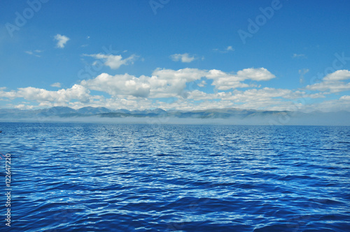 sea lanscape. blue sky, clouds over the surface of sea. mountain on horizon © Евгений Кожевников