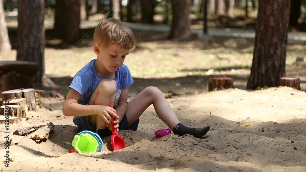 A boy plays in the sandbox with shovel and pail and shapes for sand
A boy plays in the sandbox with shovel and pail and shapes for sand