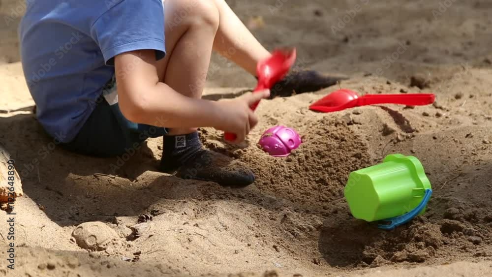 A boy plays in the sandbox with shovel and pail and shapes for sand
A boy plays in the sandbox with shovel and pail and shapes for sand