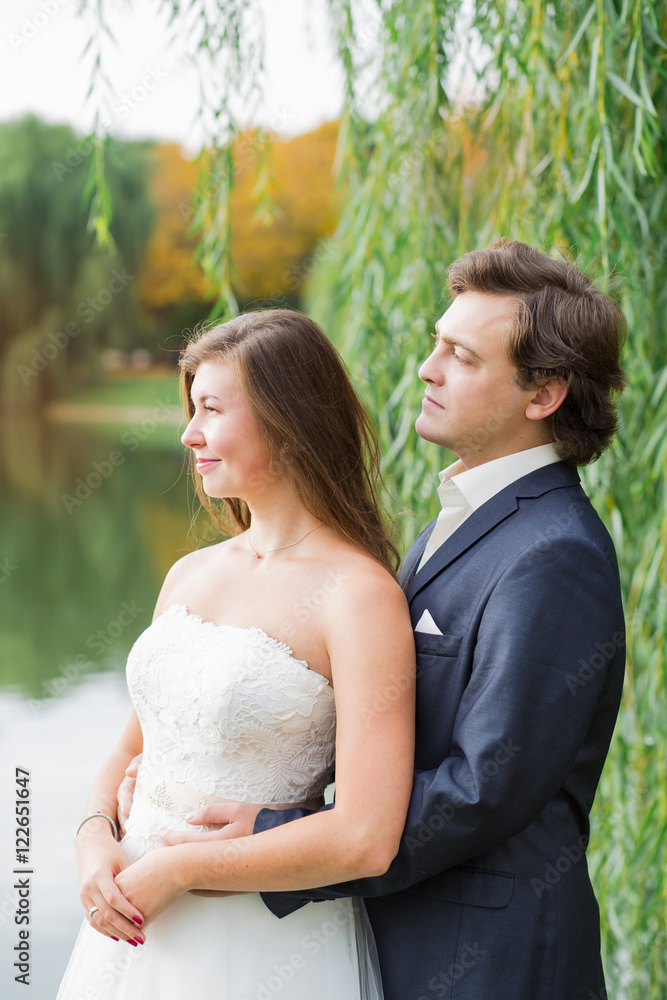 Fototapeta premium Young smiling bride and groom close portrait in summer park