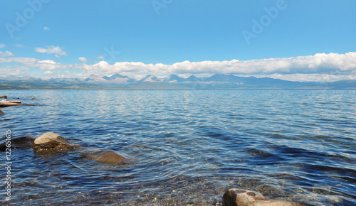 sea lanscape. blue sky, clouds over the surface of sea. mountain on horizon