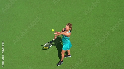 Young female tennis player serves.