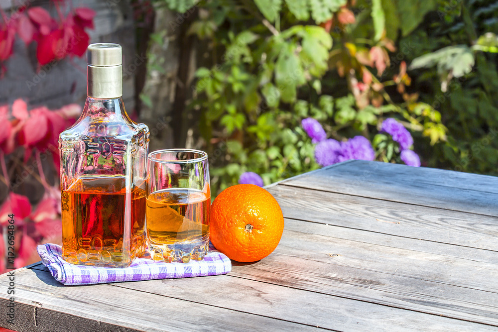 Bottle tequila with glass and lemon on old table in garden Bottle tequila with glass and lemon on old table in garden