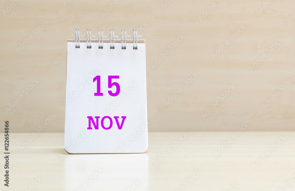 Closeup surface note book with purple 15 nov word in page on blurred brown wood desk and wood wall textured background with copy space under window light Closeup surface note book with purple 15 nov word in page on blurred brown wood desk and wood wall textured background with copy space under window light