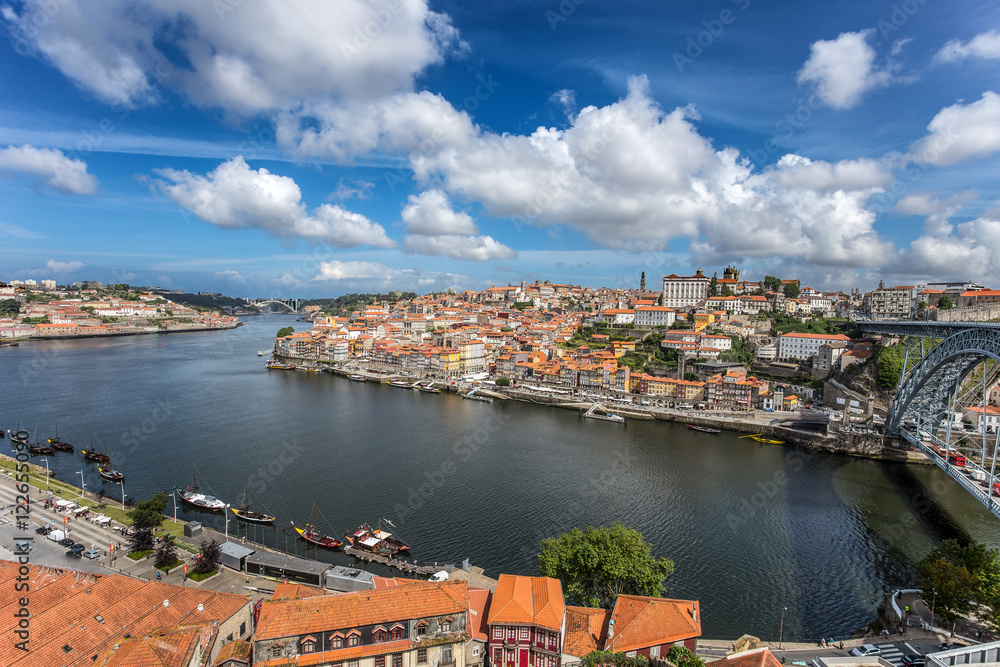 View of the historic city of Porto, Portugal with the Dom Luiz bridge. across the Douro river and the traditional rabelo boats
