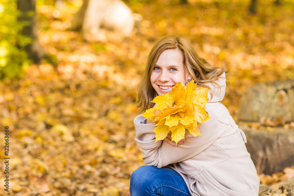 Young woman with autumn leaves in hand and fall yellow maple garden background Young woman with autumn leaves in hand and fall yellow maple garden background