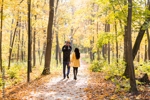 happy young family with their daughter spending time outdoor in the autumn park