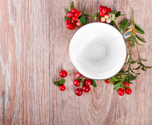 red lingonberries and empty coffee cup on wooden background