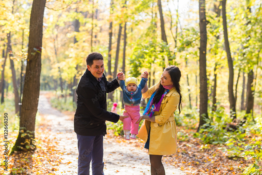 Naklejka premium happy young family with their daughter spending time outdoor in the autumn park