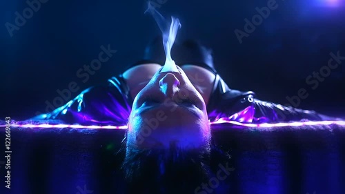 Club Party – Nightlife. Beautiful Sexy Young Glamorous Woman Relaxing in the Chill-out in Nightclub and Smoking Hookah and exhaling smoke. Chilling. Sensual Girl at the Bar. Disco neon illuminated