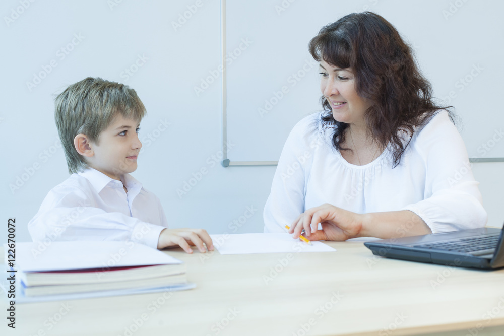 Primary school teacher and student sitting at the table Primary school teacher and student sitting at the table