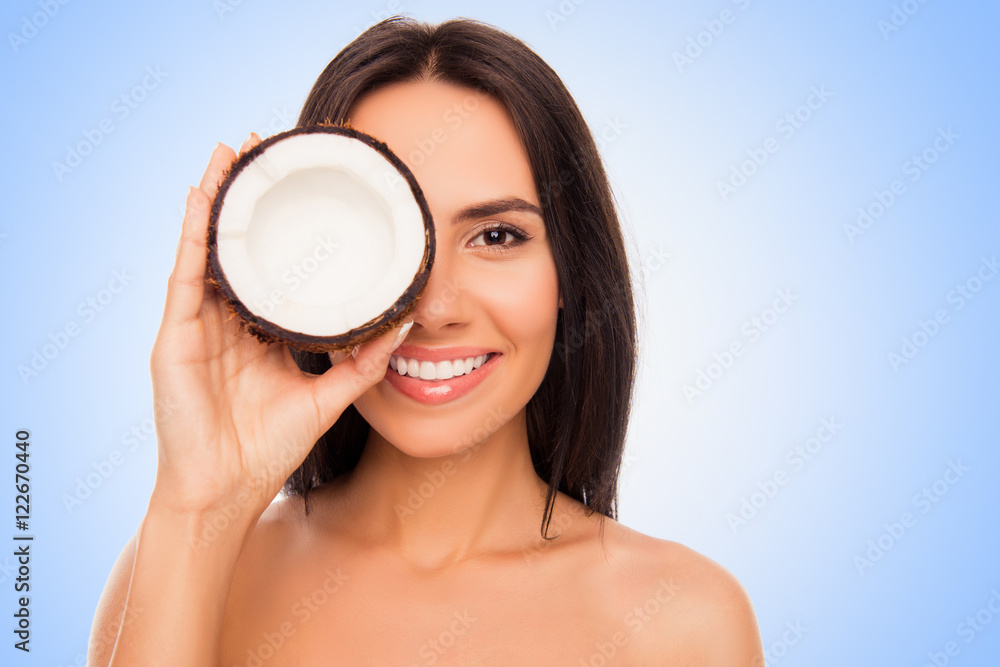 Cheerful pretty young woman holdind coconut near her eyes Cheerful pretty young woman holdind coconut near her eyes