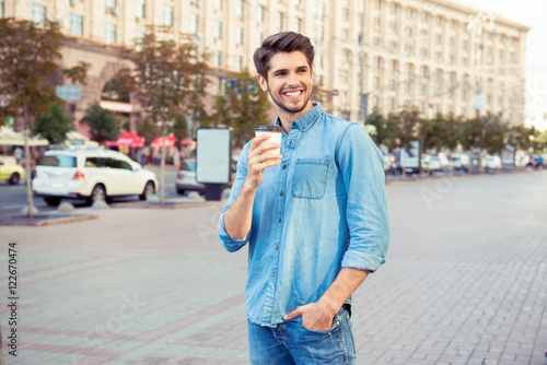 handsome  young man drink coffee and walk the city © deagreez