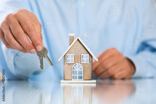 Male Hands holding Miniature House and House Key