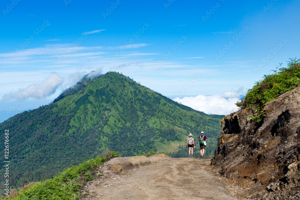 Group of hikers with backpacks walking in mountains. sky blue an