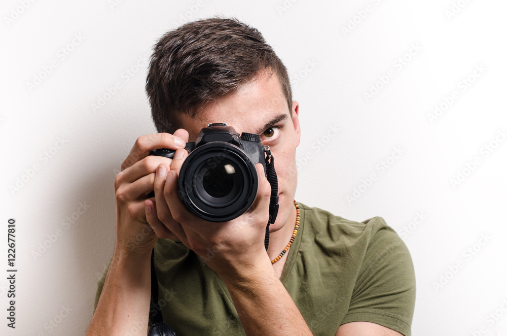 Young man taking a shot with camera. White background. Young man taking a shot with camera. White background.