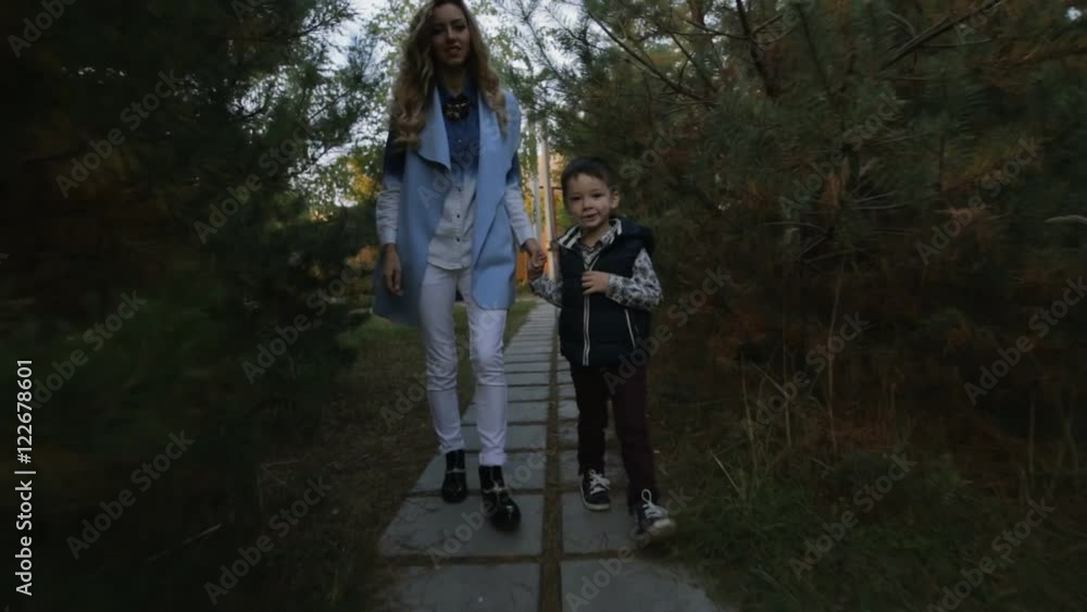 Mother with son go between pines at autumn evening Mother with son go between pines at autumn evening