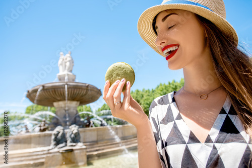 Young female tourist with macaron cookie near the famous fontain de la Rotonde in Aix-en-Provence in France photo