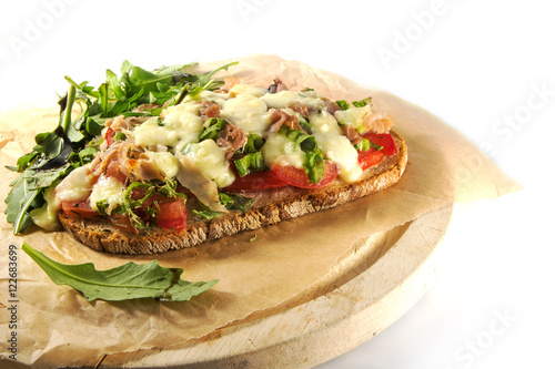 gratinated bread with tomato spring onions, bacon and mozzarella, white background