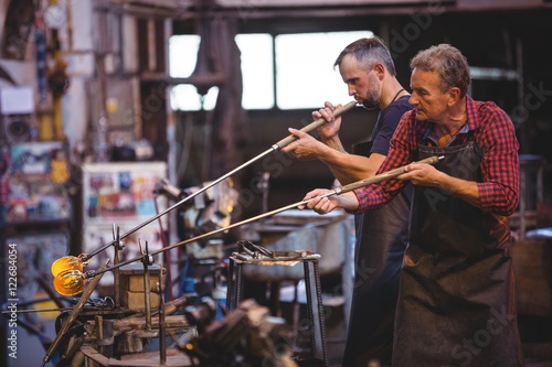 Glassblower shaping a glass on the blowpipe photo