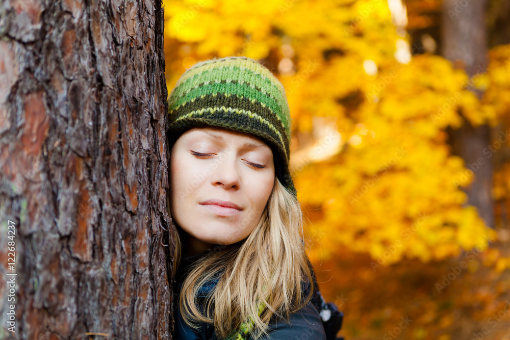 Hugging Tree Trunk in the Woods by Blonde Girl. Woman Meditating Outdoors with Closed Eyes and Tree Hug over Yellow Autumn Background. Inspirational Concept Outdoors in Beautiful Nature. Hugging Tree Trunk in the Woods by Blonde Girl. Woman Meditating Outdoors with Closed Eyes and Tree Hug over Yellow Autumn Background. Inspirational Concept Outdoors in Beautiful Nature.