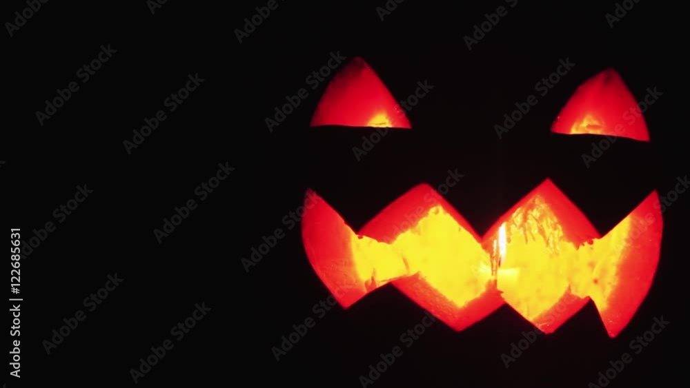 Young guy looks on burning candle inside of carved pumpkin jack o lantern face to face close up Young guy looks on burning candle inside of carved pumpkin jack o lantern face to face close up
