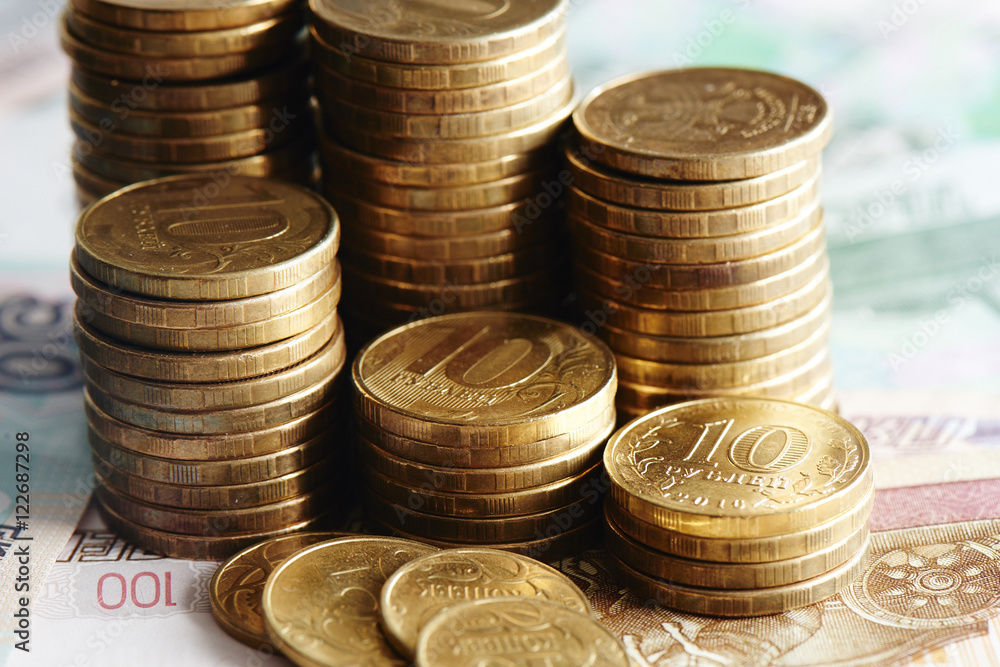 A stack of iron ruble coins lying on paper banknotes closeup A stack of iron ruble coins lying on paper banknotes closeup